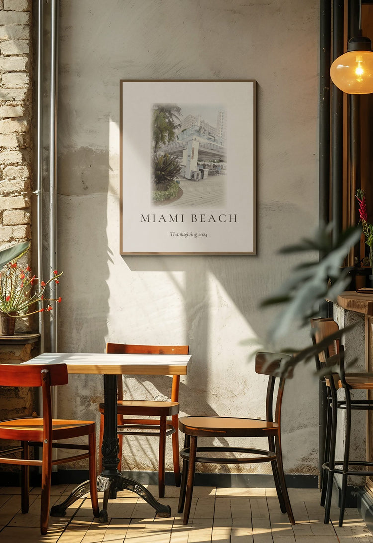 An ink and wash illustration of a Miami Beach storefront, framed on a warm brick cafe wall with wooden chairs and pendant light.