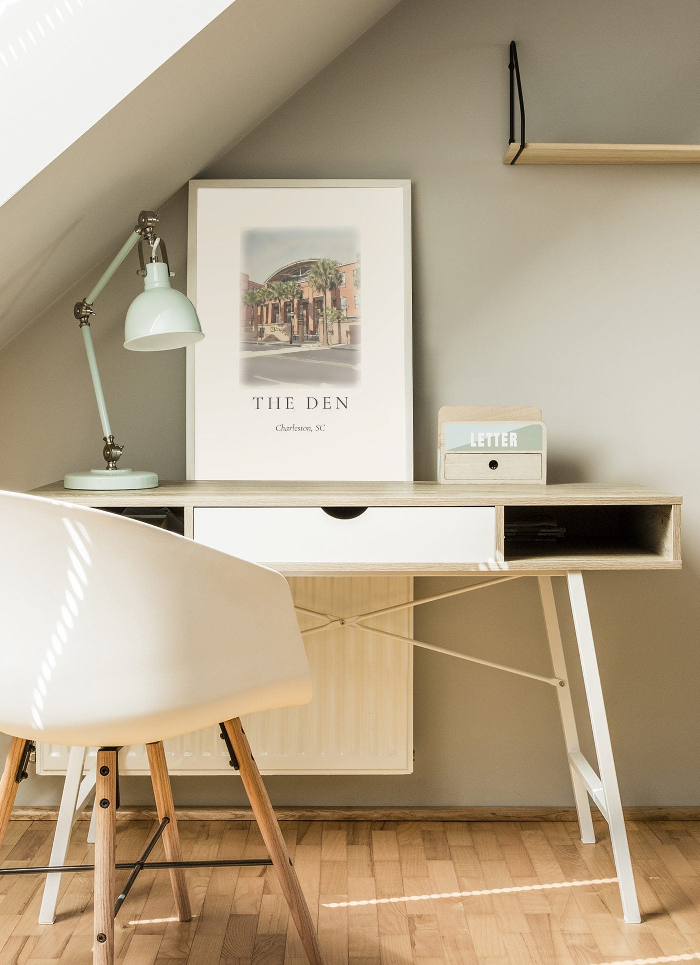 An ink and wash illustration of The Den framed above a Scandinavian study desk, soft natural light.